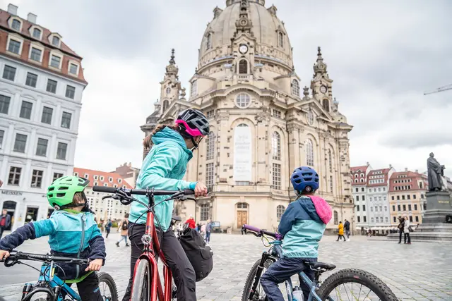 Eine Familie steht mit Fahrrädern auf dem Platz vor der Dresdner Frauenkirche.