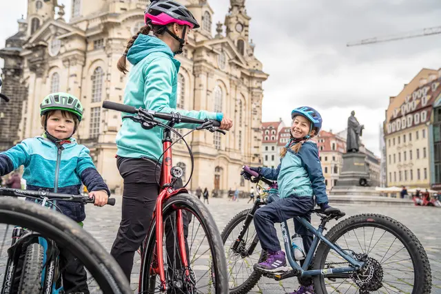 Kinder und Erwachsene stehen mit Fahrrädern vor der Dresdner Frauenkirche.