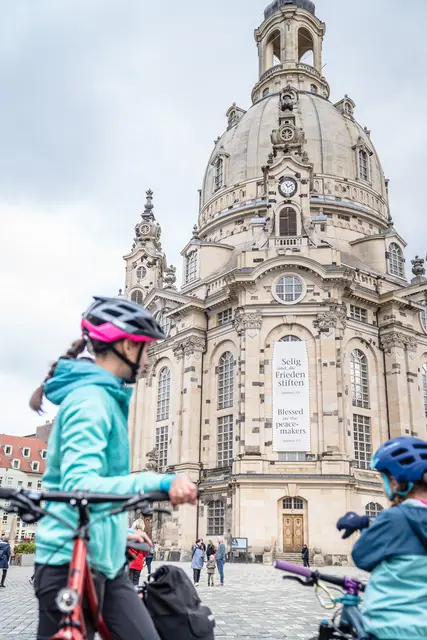 Eine Familie steht mit Fahrrädern vor der Dresdner Frauenkirche.