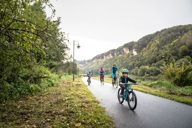 Eine Familie fährt auf einem Radweg durch das grüne Elbtal.