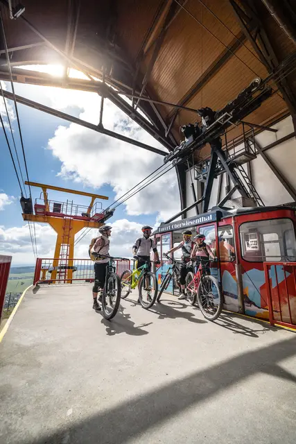 Mountainbiker stehen mit ihren Rädern an einer Gondelstation.