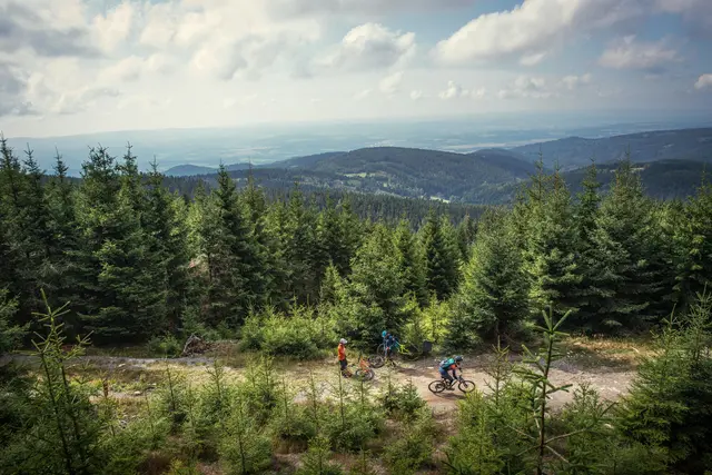 Eine Mountainbike-Gruppe fährt auf einem Höhenweg vor weitem Erzgebirgspanorama.
