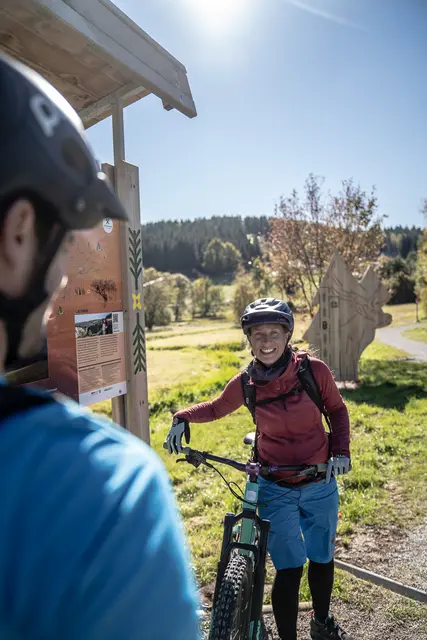 Mountainbiker besprechen ihre Tour direkt an einer Informationstafel.