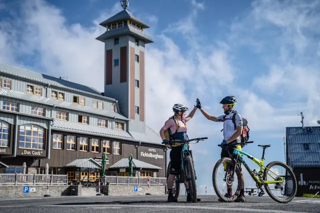 Zwei Mountainbiker stehen mit ihren Rädern vor dem Fichtelberghaus.