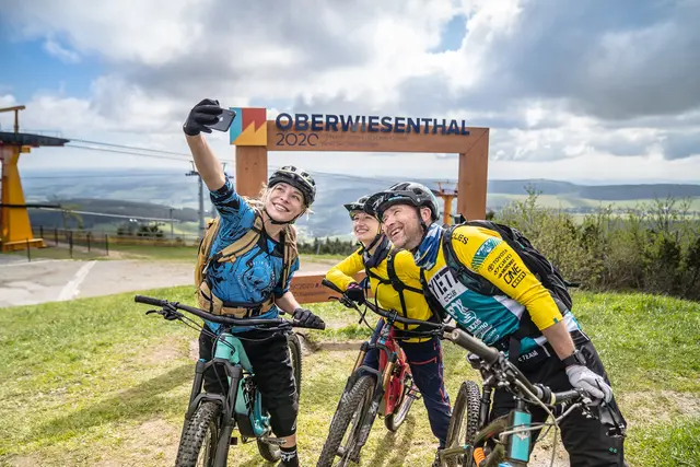 Zwei Mountainbiker machen vor dem Eingang eines Bikeparks ein Selfie.