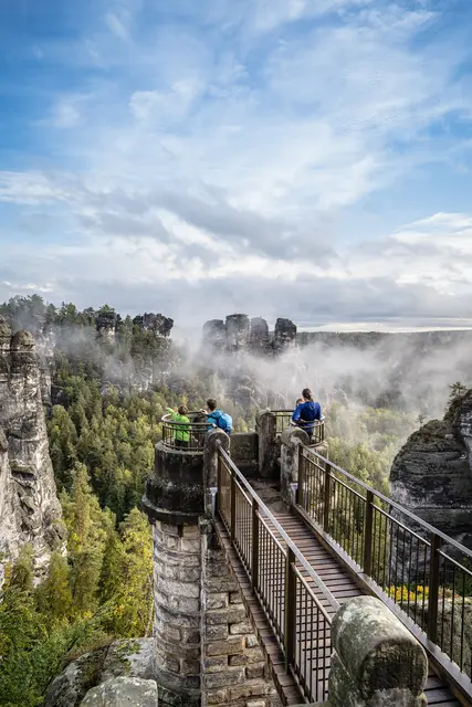 Radgäste blicken von einem Aussichtspunkt auf die Felsen und die Basteibrücke.