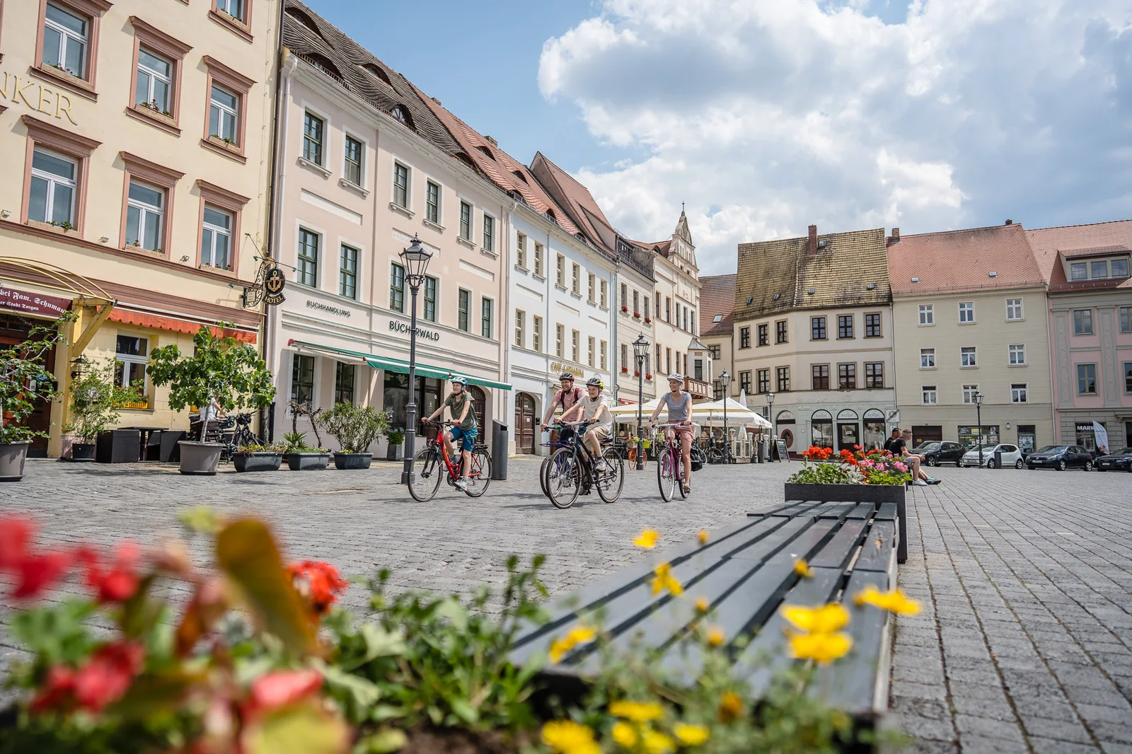 Eine Radgruppe fährt über einen historischen Marktplatz in Sachsen.