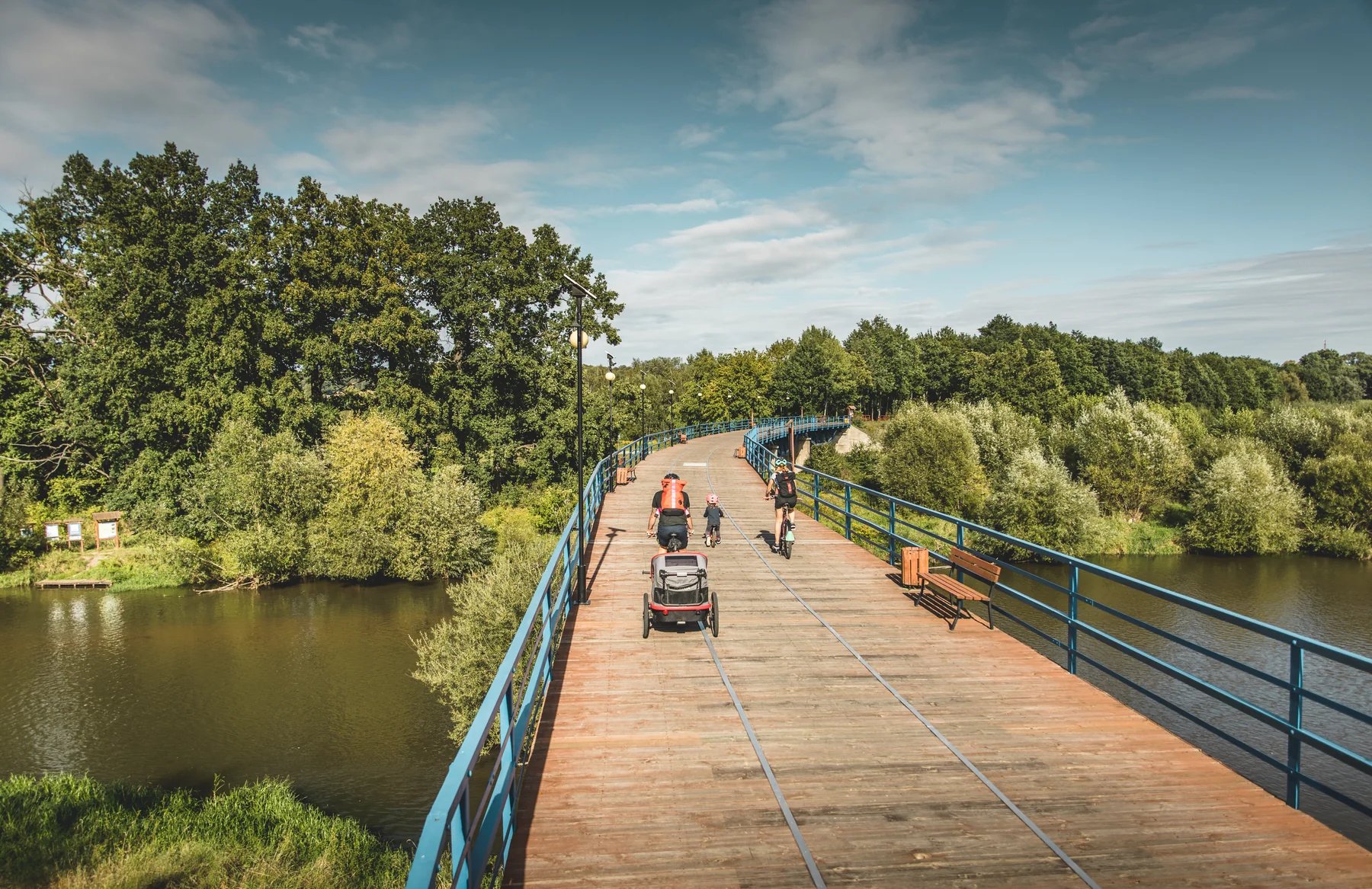 Eine Familie fährt mit Fahrrädern über eine Brücke.