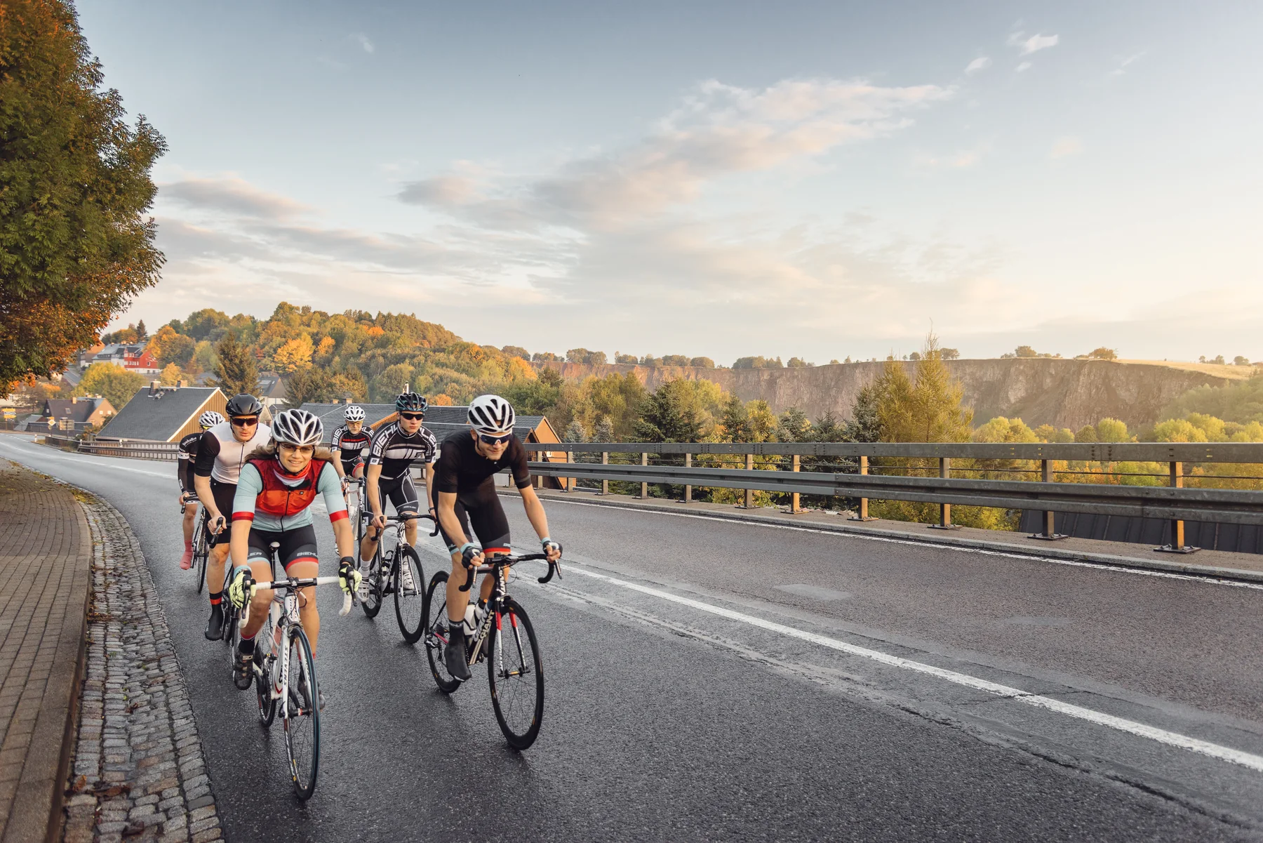 Eine Gruppe Rennradfahrender fährt durch eine sächsische Hügellandschaft.